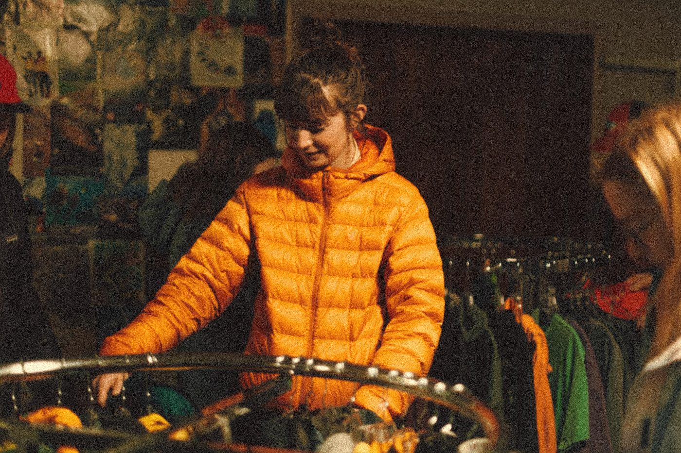 Inside Naomi Market, a shopper in an orange puffy at the racks