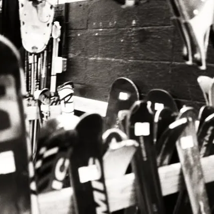 Black and white film still of skis racked in the shop, prepped for the winter season